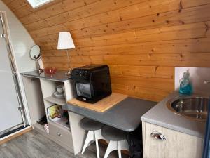 a small kitchen with a desk with a microwave at The Midi Pod in Aberystwyth