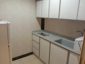 eine kleine Küche mit weißen Schränken und einer Spüle in der Unterkunft أبراج وطني in Al Bahah + 58 Fotos
