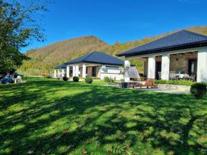a house with a green yard with a house at Holiday home Green coast in Bosanska Krupa