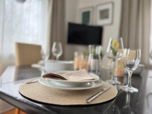 a table with a plate and two wine glasses on it at FeWo Pelkmann Apartment 1 - Die Grüne Oase - Garten & Terrasse in Weikersheim