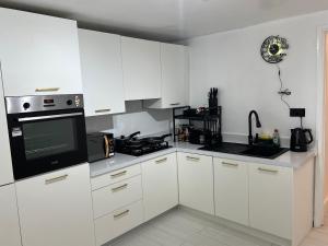 a kitchen with white cabinets and a black microwave at Intimate Hot Tub Pad in Swanscombe
