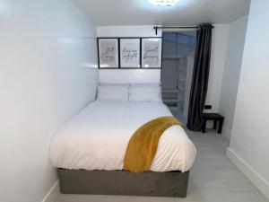 a bedroom with a bed with white sheets and yellow blanket at Intimate Hot Tub Pad in Swanscombe