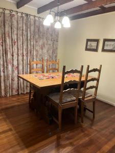 a dining room table with four chairs and a curtain at Casa Krampus Hospedaje y Cervecería in Valdivia