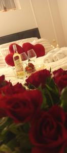a bed with two bottles and red roses on it at Agroturystyka W kurniku z jacuzzy in Lubań
