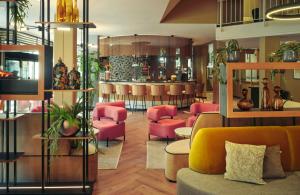 a lobby with pink chairs and a bar at Leonardo Royal Hotel Baden- Baden in Baden-Baden