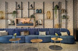 a living room with a blue couch and two tables at Leonardo Royal Hotel Baden- Baden in Baden-Baden +69 photos