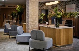 a waiting room with chairs and a counter with flowers at Leonardo Royal Hotel Baden- Baden in Baden-Baden