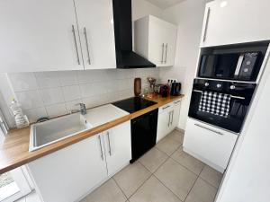 a white kitchen with a sink and a microwave at Maison individuelle parking privé et gratuit in Sainte-Savine