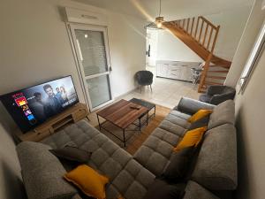 a living room with a couch and a tv at Maison individuelle parking privé et gratuit in Sainte-Savine