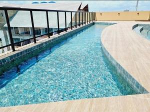 a swimming pool with blue water next to a building at Flat Completo Porto de galinhas in Porto De Galinhas