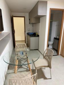 a room with a glass table and chairs and a kitchen at Flat Completo Porto de galinhas in Porto De Galinhas