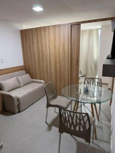 a living room with a glass table and a couch at Flat Completo Porto de galinhas in Porto De Galinhas