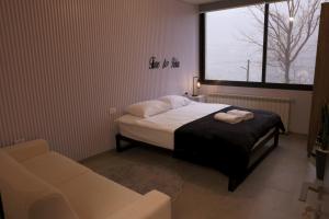 a bedroom with a bed and a couch and a window at Domaine De Faraya F2 in Nab‘ al Maghārah