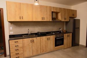 a kitchen with wooden cabinets and a stainless steel refrigerator at Domaine De Faraya F2 in Nab‘ al Maghārah