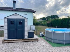 a small shed next to a bath tub next to a house at Maison avec piscine in Golbey