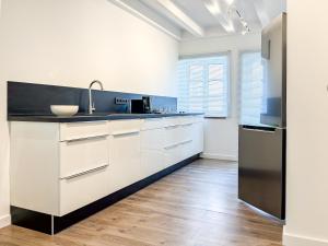 a kitchen with white cabinets and a black refrigerator at Gutshaus am Rhein in Düsseldorf