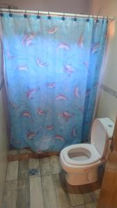 a bathroom with a toilet with a fish shower curtain at Cabaña Mailin II in Uspallata