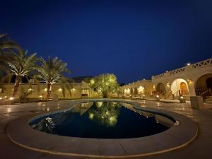 a courtyard with a swimming pool at night at SiwaTu Lodge in Siwa