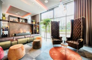 a living room with two chairs and a couch at Leonardo Royal Hotel Ulm in Ulm