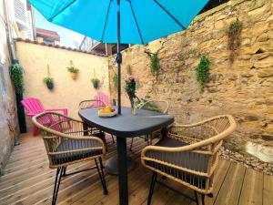 a table with chairs and a blue umbrella on a patio at L'escale Charliendine in Charlieu