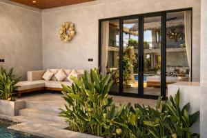 a living room with a couch and a swimming pool at Bella Vida Resort, Uluwatu in Uluwatu
