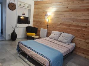 a bedroom with a bed with a wooden wall at L'escale Charliendine in Charlieu