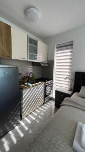 a bedroom with a bed and a kitchen with a window at Apartman studio BMB 1 in Bukorovac