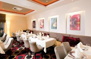 a dining room with white tables and white chairs at Leonardo Hotel Hannover Airport in Hannover +41 photos