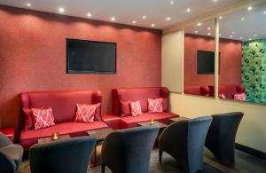 a waiting room with red chairs and a table at Leonardo Hotel Mönchengladbach in Mönchengladbach