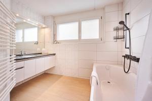 a white bathroom with a tub and a sink at Chalet in Thun, modern, spacious, perfect location in Thun +41 photos