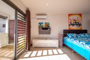 a bedroom with a bed and a flat screen tv at Studio Coquet - Mautara Lodge in Bora Bora