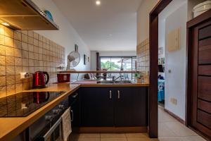 a kitchen with black cabinets and a sink at Studio Coquet - Mautara Lodge in Bora Bora