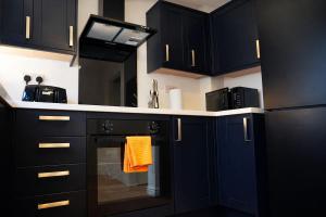 a kitchen with black cabinets and an oven with an orange towel at Preston Central in Preston