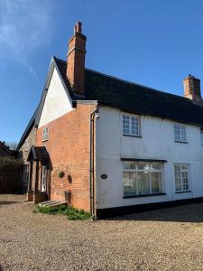 an old white house with a brick building at The Old Stores in Bury Saint Edmunds