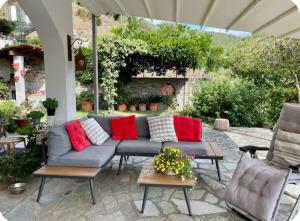 a patio with a gray couch and red pillows at Eucalipto in Sestri Levante
