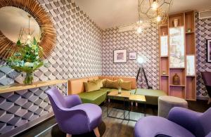 a living room with purple and green chairs and a couch at Leonardo Hotel Wolfsburg City Center in Wolfsburg +46 photos