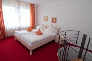 1 dormitorio con 1 cama con sábanas blancas y almohadas de color naranja en Haus Siegfried Appartements, en Xanten