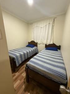 two beds in a small room with a window at Apartamentos Lourdes in Antofagasta