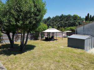 a yard with two trees and an umbrella and a building at Ombre d'été in Ruoms