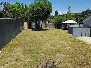 a grassy yard with a fence and a tree at Ombre d'été in Ruoms