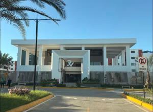 a white building with a palm tree in front of it at Relaxing & New Retreat 3 bedroom riviera Verde in Santo Domingo
