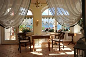 ein Esszimmer mit einem Tisch, Stühlen und Fenstern in der Unterkunft Hotel Schloesschen am See in Reschen