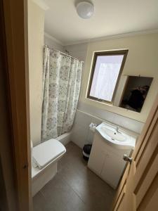a bathroom with a sink and a toilet and a window at Apartamentos Lourdes in Antofagasta