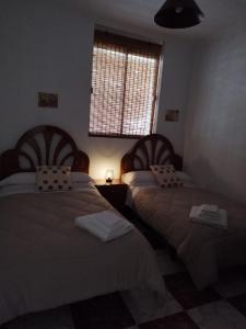 two beds in a room with a window at La Cañada in Baena