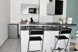 a kitchen with two bar stools and a counter top at La Cachette Ludique in Orléans +8 photos