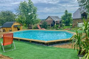a swimming pool in a yard with a chair at La grange de Moli in Vigeois +3 photos