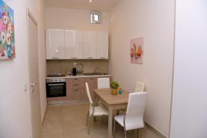 a kitchen with a wooden table and white chairs at Dimora Borbonica 1 in Marcianise