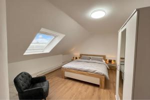 a bedroom with a bed and a chair and a window at Sky Loft Schwarzach in Schwarzenbruck