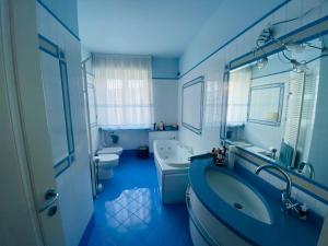 Ein blaues Badezimmer mit zwei Toiletten, Badewanne und Waschbecken in der Unterkunft Rainerio 06 in Fano + 8 Fotos