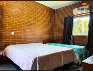 a room with two beds and a brick wall at Chácara Galileia in Trindade +3 photos